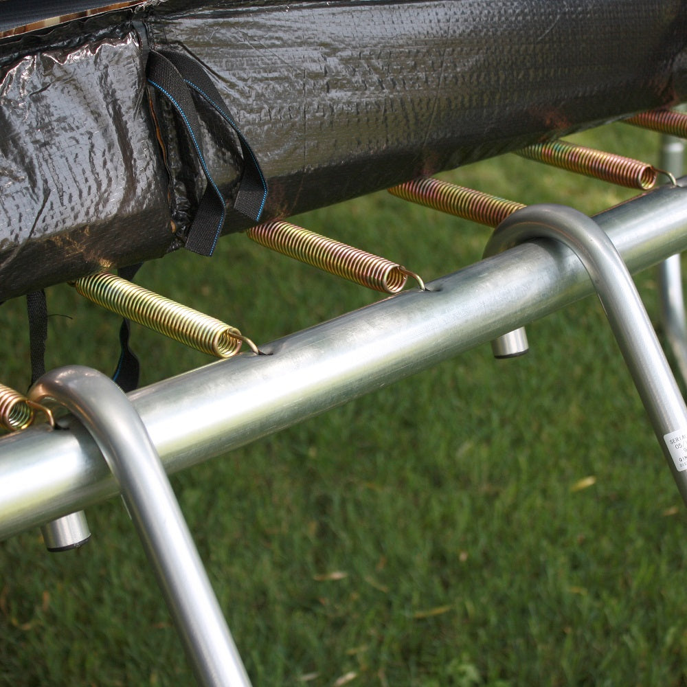 The trampoline’s spring pad is lifted up so the trampoline ladder can be hooked onto the trampoline frame. 